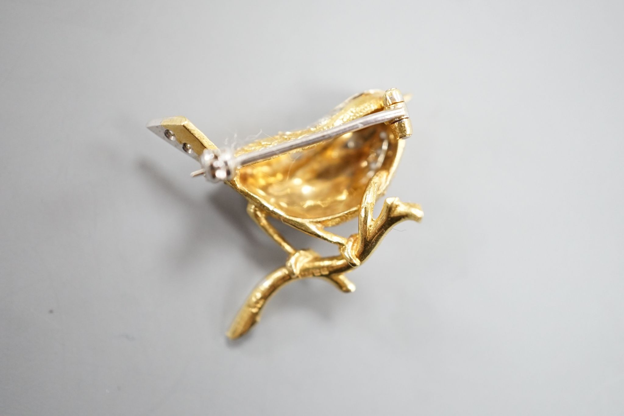 A modern textured 18ct two colour gold, ruby and diamond set bird brooch, 24mm, gross weight 6 grams.